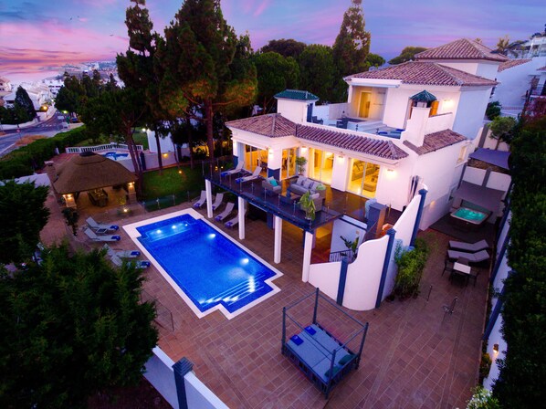 aerial night shot of pool and villa with la cala de Mijas  in the back ground.