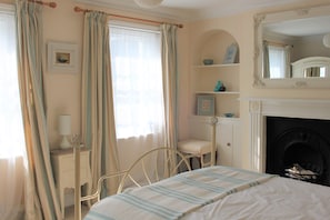 Master bedroom with king sized bed and two windows, on the first floor.