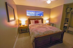 Queen bedroom with open shelving and ceiling fan.