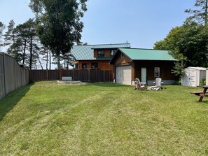 Large fenced yard with firepit, chairs and picnic table