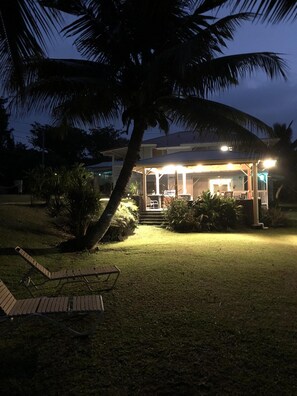 Late evening view of outdoor patio from ocean side lawn.