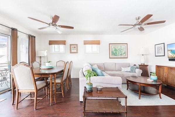The main living area includes a dining table for 6, sectional couch, cable TV, and sliding doors that open to the balcony.
                