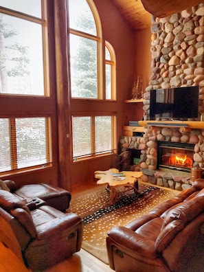 Two story real fieldstone wood burning fireplace with view to lake.