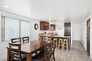 Dining table and nearby barstool seating sit adjacent to the kitchen on one side and living room on the other.
                