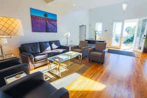 The living room features leather couches, hardwood floors and elevated ceilings.