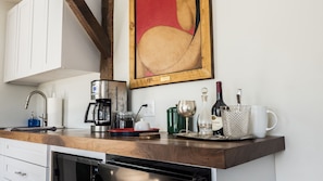 Walnut topped kitchenette counter with coffee maker. 