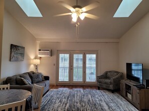 Vaulted ceiling living room has two skylights, queen sofa bed, AC, and Smart TV