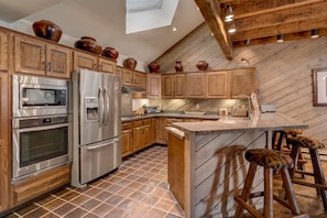 Large Kitchen and Bar with Skylight, Stone Slab Counters, and Stainless Steel Appliances