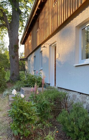 Eingang Ferienwohnung. Kräutergarten und kleine Terrasse mit Abendsonne