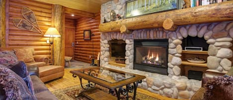 The living area features a TV and fireplace below an oversize natural log mantle