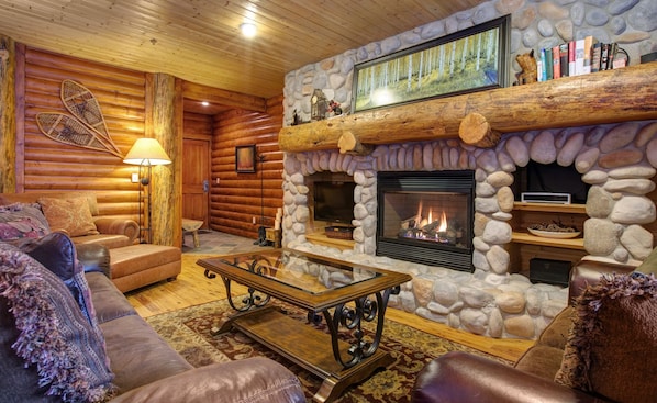 The living area features a TV and fireplace below an oversize natural log mantle