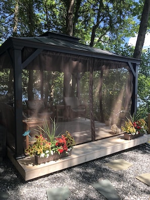 Screened in gazebo at waterfront with mini fridge.