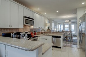 Kitchen is open and bright looks out to eating area and game area.