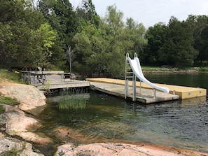 Floating dock,  slide, large deck with bench seating, table andoutdoor fire ring