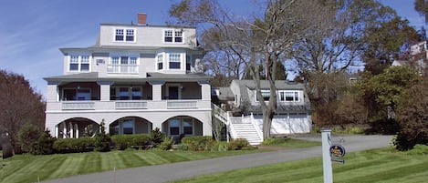 Front of SNI Cottage, showing various verandas, oceanview windows, lawn.