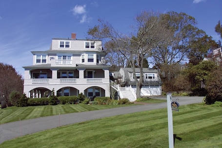 Front of SNI Cottage, showing various verandas, oceanview windows, lawn.