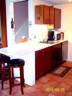 Kitchen with end of counter seating for two across from dining area.