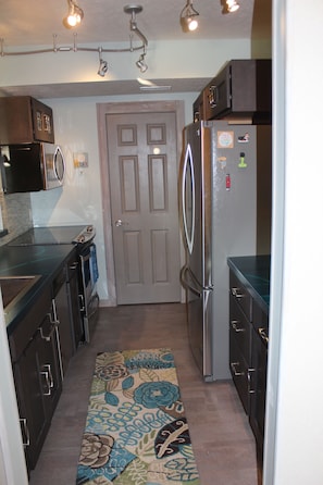 Galley kitchen w/ stove, microwave, dishwasher, and full size refrigerator