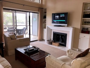 Living room with vaulted ceiling and sliding glass door to screened porch