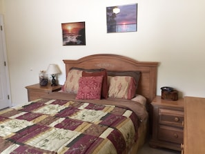 Front bedroom with queen bed, dresser, mirror, armour, and two nightstands. 