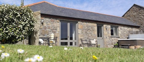 Exterior of Brea Cottage with sunny dining patio, hot tub, and large garden. 