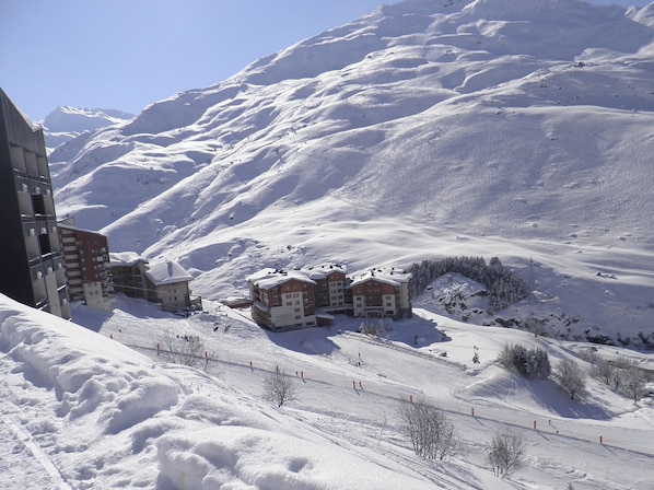 View of apartment building (2nd left lighter wood) and ski on/off pieste below