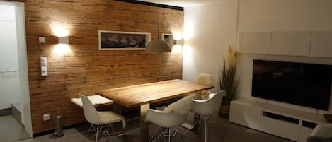Wohnzimmer mit Holztisch, Holzwand und Smart TV im Wander- und Aktivchalet