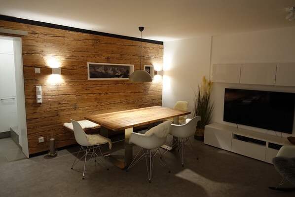 Wohnzimmer mit Holztisch, Holzwand und Smart TV im Wander- und Aktivchalet