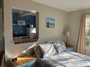 View of queen bed with kitchen beyond