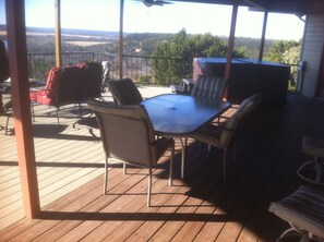 Covered deck with table, lots of seating and hot tub