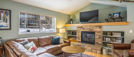 Sunny living room with fireplace, 55" TV, & sound bar.