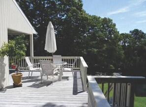 View from deck with gas barbque, eating area, outdoor furniture.