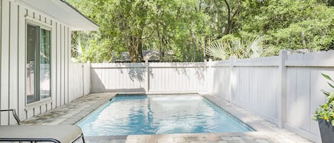 Fenced in backyard with pool, grill, table and loungers