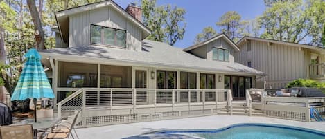 Back of house with screened porch, raised deck and  table and chairs on pool deck