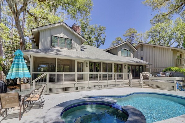 Back of house with screened porch, raised deck and  table and chairs on pool deck