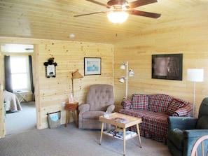 Living room showing seating area, ceiling fan and entrance to bedroom #1.