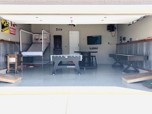 Garage Rec Room featuring epoxy floor, Pop-A-Shot, darts, built-in speakers & TV