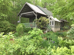 Back of lodge, covered porch overlooking small pond and back garden