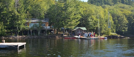 The view of the cottage and boathouse from the lake, and  the family on the dock