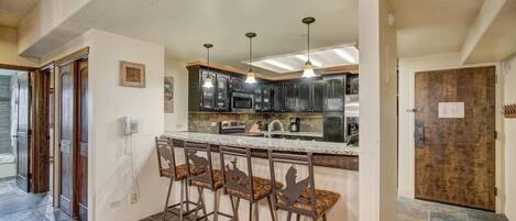 Kitchen features slab granite, stainless appliances and seating for 4 at bar.