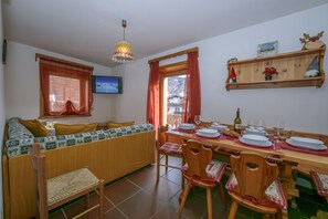 Salle de séjour ouverte avec coin repas et accès au balcon.