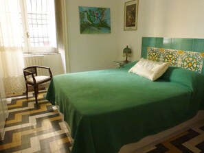 Green room decorated with Vietri ceramics. It has a double bed.