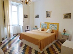 Yellow room decorated with Vietri ceramics. It has a double and single bed.