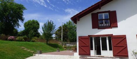 Vue sur la location, sa terrasse et le jardin