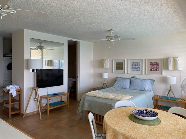 Common area with mattress, dinning table, and wall-mounted 4K smart TV with Roku