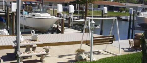 Back yard with dock, table, swing, and chairs.