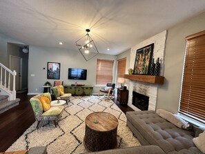 Spacious living room with smart TV and fireplace. Opens up to kitchen and dining