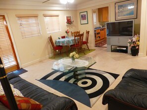 Living room with coffee table, TV and eating area with kitchen entry