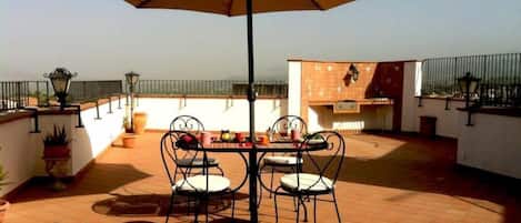 Ampio terrazzo con ombrelloni e sedie per fare colazione o cenare all'aperto