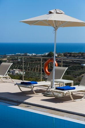 The pool area is equipped with sun beds and umbrellas.